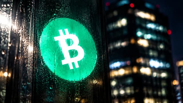 Lichtreflex mit dem Bitcoin-Cash-Zeichen auf einer regennassen Glasscheibe vor den Lichtern eines nächtlichen Büroturms