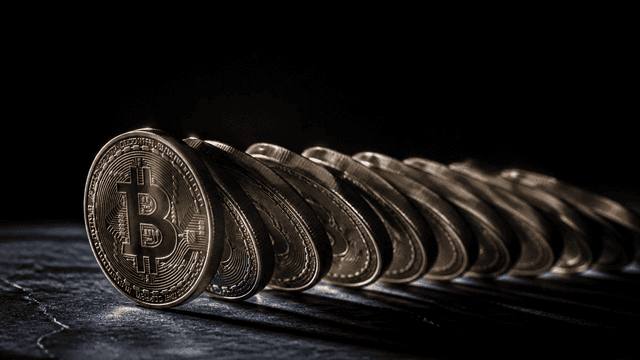 Eine Reihe physischer Münzen kippt geschlossen in dieselbe Richtung wie eine Dominoreihe, die vorderste trägt das Bitcoin-Zeichen