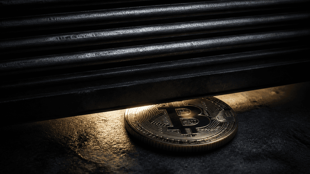Herabfahrendes Stahl-Rolltor, im letzten Lichtspalt eine physische Münze mit eingeprägtem Bitcoin-Zeichen