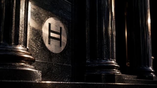 Nächtliches Säulenportal aus dunklem Granit mit dem Hedera-Zeichen als Metallintarsie in der Steinwand