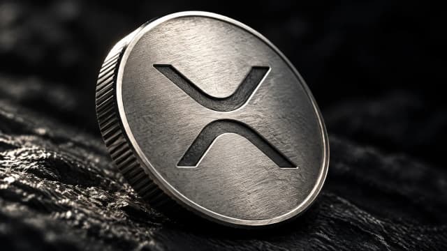 Silbermünze mit eingeprägtem XRP-Zeichen auf dunklem Schiefer