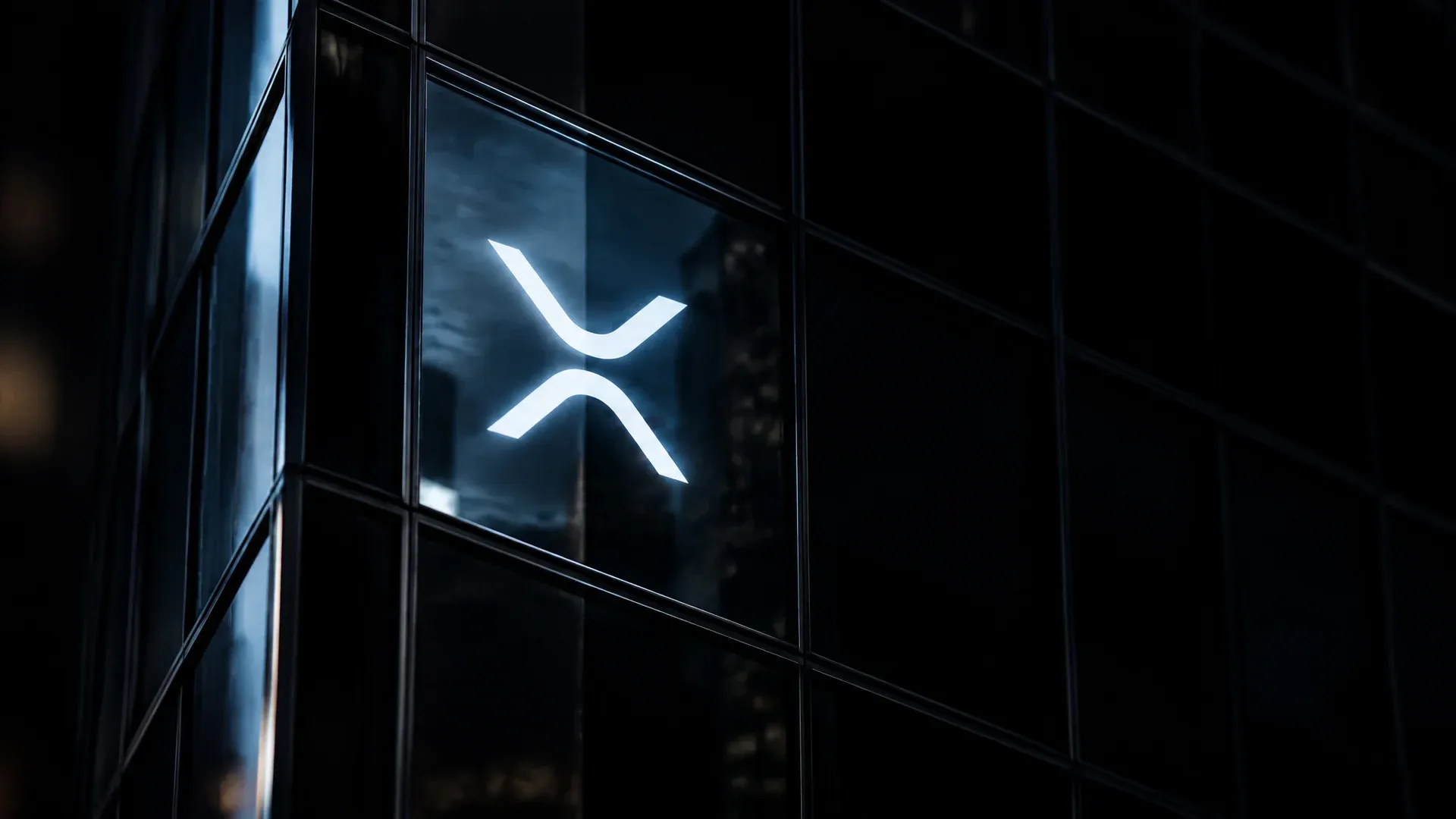 Dunkle Glasfassade eines Bürohochhauses bei Nacht, in einer Scheibe leuchtet das XRP-Zeichen als heller Reflex