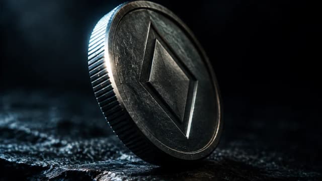 Schwere Metallmuenze mit tief eingepraegtem rautenfoermigem Symbol, schraeg auf dunkler Steinflaeche im Streiflicht