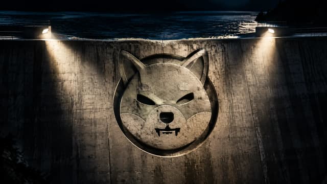 Betonstaumauer bei Nacht mit hoch angestautem Wasser, in die Mauer ist das Shiba-Inu-Zeichen als Relief eingelassen