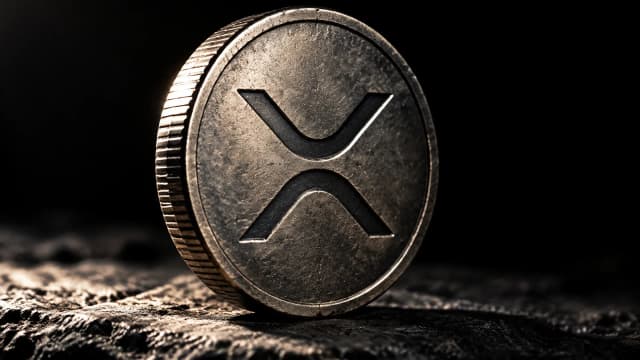 Schwere gepraegte Metallmuenze mit dem XRP-Zeichen aufrecht auf einer Steinplatte im harten Seitenlicht